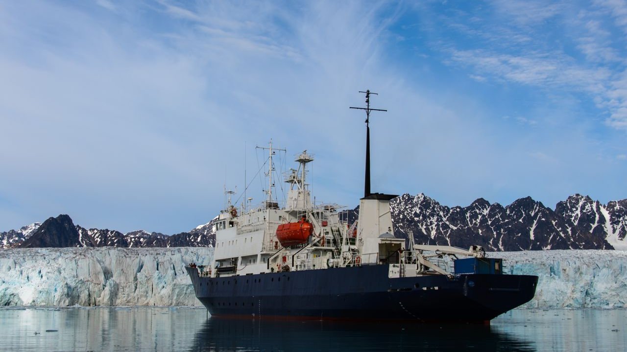 Icebreaker on the water in front of ice and mountain landscape